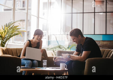 Two businesspeople having meeting in cafe. Smiling business colleagues working together in office lobby. Stock Photo