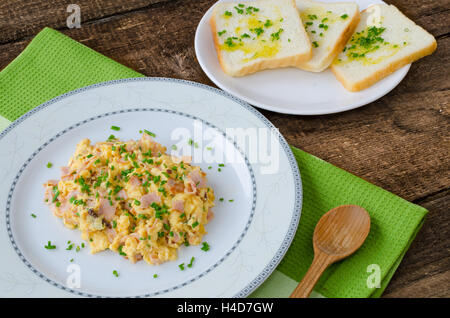 Scrambled eggs with chive and bacon, toast with herbs on wood table Stock Photo