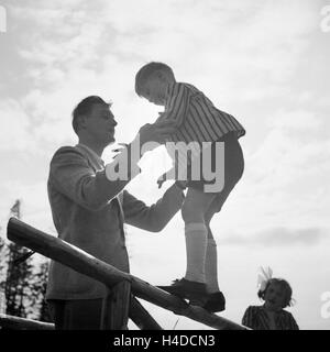 Ein Mann hält einen kleinen Jungen, der auf einem Geländer balanciert, Deutschland 1930er Jahre. A man holding a little boy who is balancing on a railing, Germany 1930s.