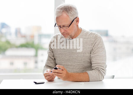 senior man with glucometer checking blood sugar Stock Photo