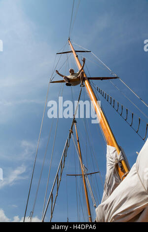 Older man on his sailing ship, sits on the mast, gesture, freedom feeling Stock Photo