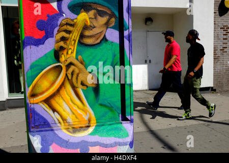 Pedestrian on 125th street in Harlem with a musician mural in front.New York City,USA Stock Photo