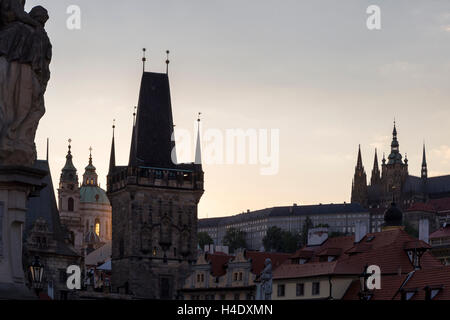 Dust motes caught in setting sun behind towers of Charles Bridge, cathedral at Prague castle and St Nikolas (Nicholas) Church. Stock Photo