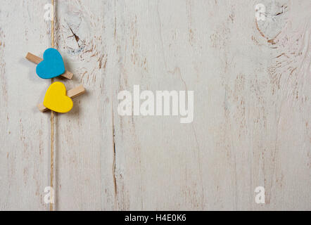 Two hearts of blue and yellow clothes pegs on a white background old Stock Photo