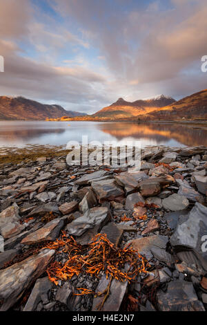 The Pap of Glencoe and surrounding mountains on the slate shores of Loch Leven in the Scottish Highlands in winter time Stock Photo