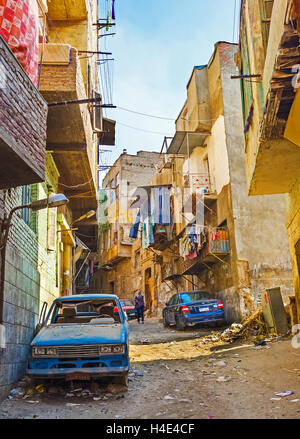 The dusty hilly street in Bab Al Khalq district with abandoned car on the foreground and the piles of garbage on the dirt road Stock Photo