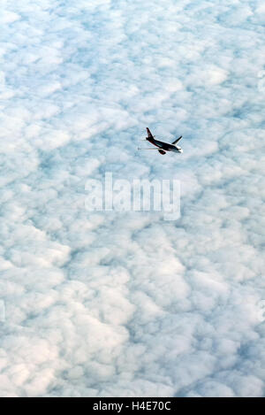 View from above of an airplane flying above a dense white cloud layer Stock Photo