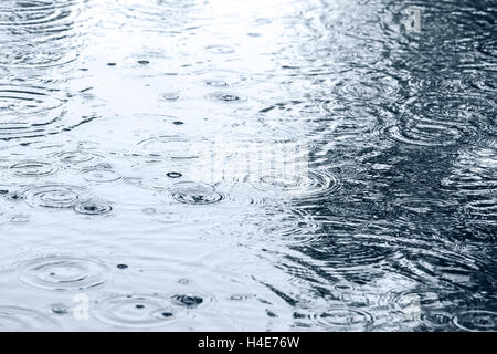 rain drops rippling in puddle with sky reflection Stock Photo