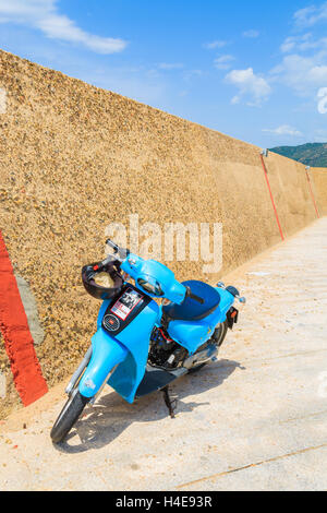 PORTO GIUNCO HARBOUR, SARDINIA - MAY 25, 2014: classic blue scooter parks in Porto Giunco port, Sardinia island, Italy. Many tourists visit Sardinia island in summer time and ride retro style scooters Stock Photo
