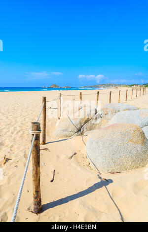 Wooden poles of a fence on beautiful golden sand Chia beach, Sardinia island, Italy Stock Photo