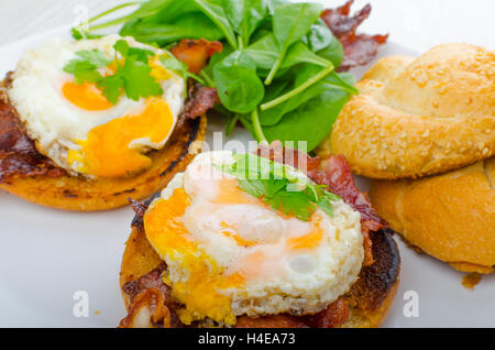 Eggs benedict with bacon and spinach on white plate Stock Photo
