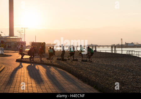 Group of men and women doing a Military Fitness bootcamp exercise workout on the beachfront at sunrise, Brighton & Hove UK Stock Photo