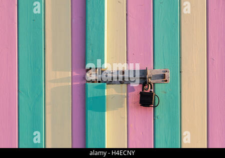 Close up of padlock and lock on a wooden shed or beach hut door painted in pastel colours (pink green yellow) Stock Photo