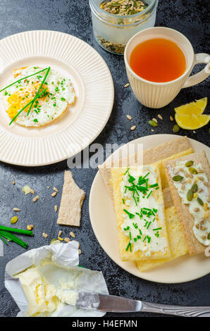Crisp Crispbread with curd cheese spread with chives and seeds, fried egg and morning tea Stock Photo
