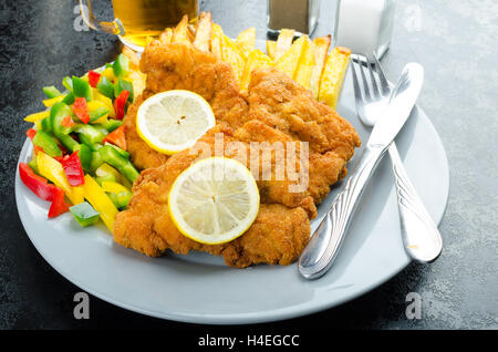 Schnitzel with french fries, homemade, platter, czech beer, vegetable, lemons Stock Photo