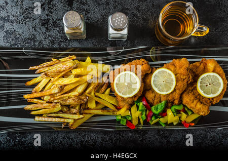 Schnitzel with french fries, homemade, platter, czech beer, vegetable, lemons Stock Photo