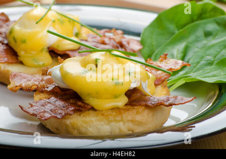 Eggs bvenedict with chives and fresh juice, spinach leaves, bio eggs Stock Photo