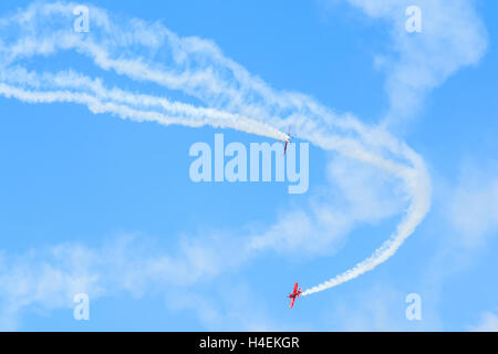 KRAKOW MUSEUM OF AVIATION, POLAND - JUL 27, 2014: two red acrobatic planes flying on blue sky at airshow in Krakow, Poland. In summer often airshows take place here. Stock Photo