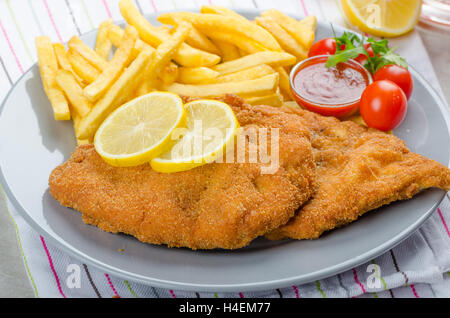 Schnitzel with french fries and a spicy dip, fresh from red orange Stock Photo