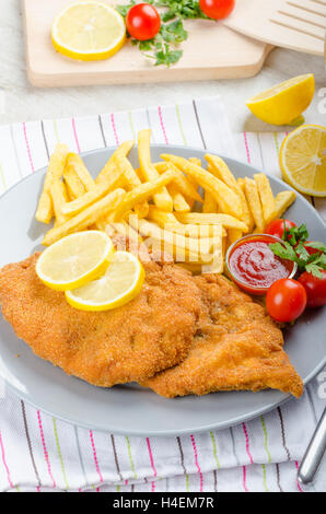 Schnitzel with french fries and a spicy dip, fresh from red orange Stock Photo