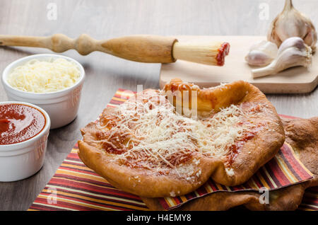 Traditional carnival fast food specialty, fried yeast dough with cheese, ketchup and garlic Stock Photo