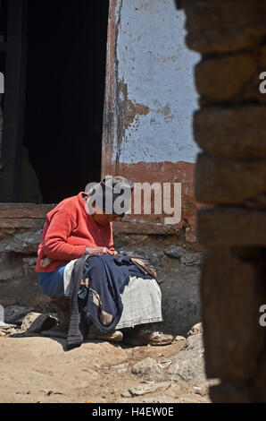 An old woman does some sewing in the street, Nele, Solukhumbu, Nepal Stock Photo