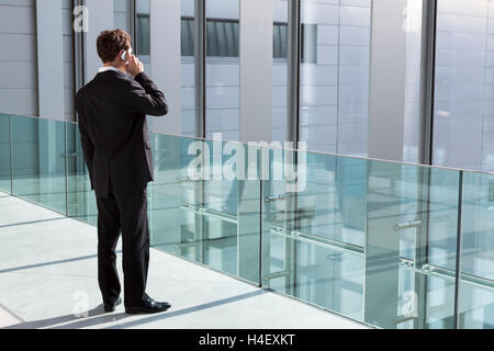 Businessman phoning with new technology smartphone in modern office building Stock Photo