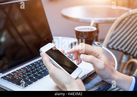 Using mobile phone and laptop outside with a cup of coffee Stock Photo