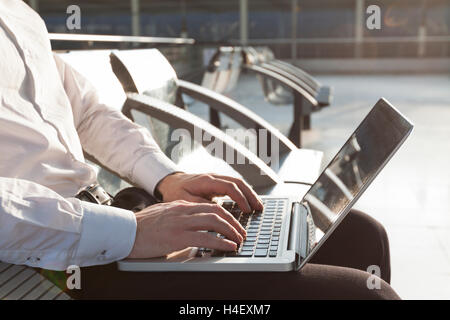 Businessman in airport waiting lounge typing on laptop Stock Photo