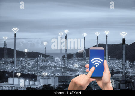 Hand holding smartphone control wireless communication network smart factory and Internet of Things. Smart factory concept. Stock Photo