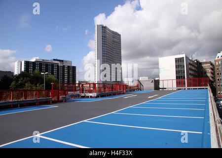 Top floor level of a car park, empty spaces, cityscape behind Stock Photo