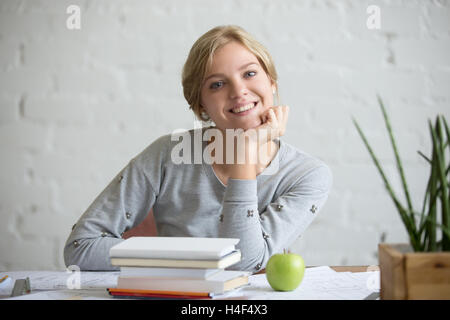 Portrait of smiling girl at desk with books and apple Stock Photo