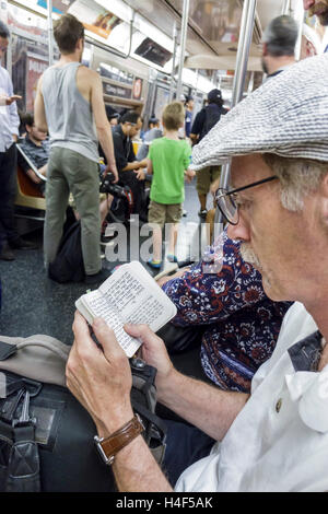 New York City,NY NYC Lower Manhattan,Chinatown,subway,train,MTA,passenger passengers rider riders,sitting,reading,Hebrew,book,language,adult,adults,ma Stock Photo