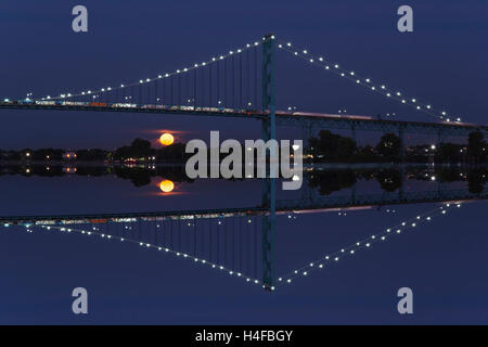 FULL MOON SETTING BELOW AMBASSADOR BRIDGE DETROIT RIVER DETROIT MICHIGAN USA Stock Photo