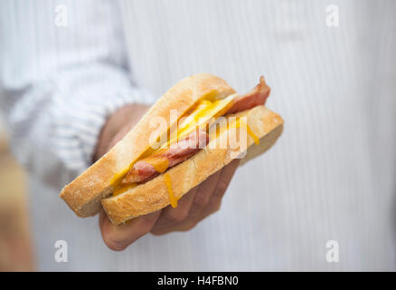 Man holding a fried egg and bacon sandwich Stock Photo