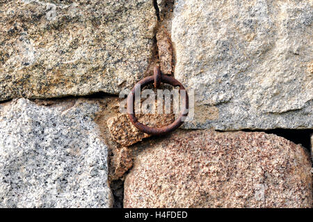 Aged metal ring and rusted by time set at a stone wall Stock Photo