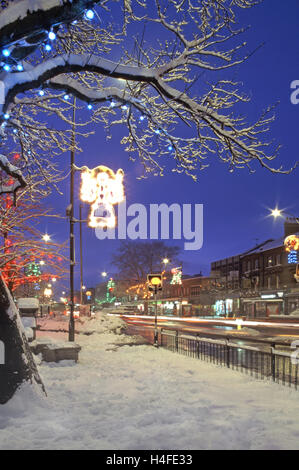 Brentwood Essex UK high street Christmas decoration on winter tree & lamp posts at dusk after snow storm (not Christmas day) Stock Photo