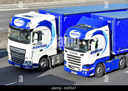 Close up two lorry cabs & trailer with driver from Maritime logistics company hgv truck drivers stuck in cab in traffic jam on m25 England UK motorway Stock Photo