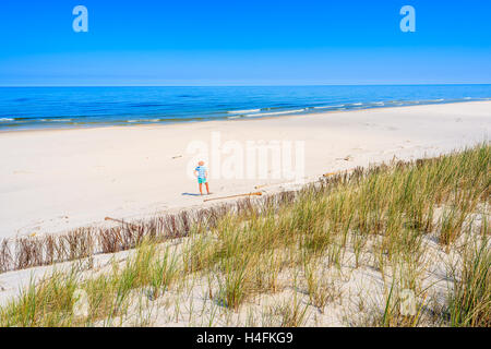 A young tourist woman standing on sandy beach in Lubiatowo coastal village, Baltic Sea, Poland Stock Photo