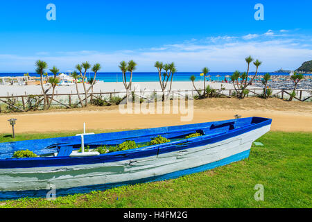 Blue and white colour fishing boat as flower pot on coastal promenade near Porto Giunco beach, Sardinia island, Italy Stock Photo