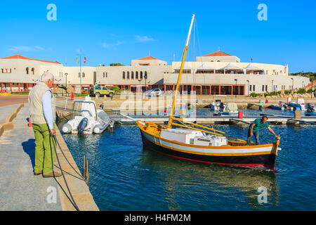 PORTO GIUNCO PORT, SARDINIA - MAY 27, 2014: fishing boat returns from open sea to Porto Giunco port. Many fishermen anchor boats here and sell fresh fish to restaurants in the harbour. Stock Photo