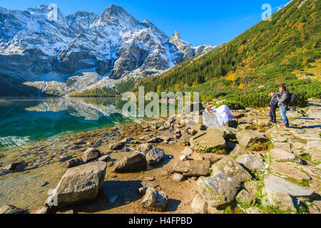 MORSKIE OKO LAKE, TATRA MOUNTAINS - SEP 28, 2014: bride in white wedding dress being photographed at famous lake in Tatra Mountains, Poland. Stock Photo
