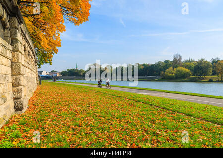 Couple of unidentified people riding bikes along a Vistula river in Krakow on sunny autumn day. Krakow is most visited city in Poland among foreign tourists. Stock Photo