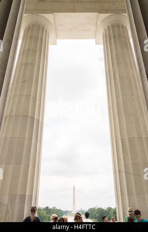 Upward view of the columns in the Lincoln Memorial with tourists and the Washington Monument in the distance Stock Photo