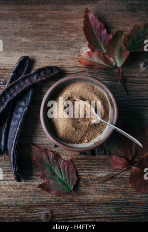 Carob pods and carob powder on wooden table Stock Photo