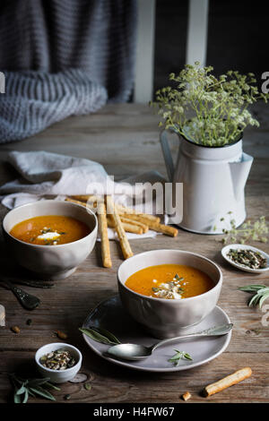 Pumpkin cream soup in grey bowls on rustic wooden table Stock Photo