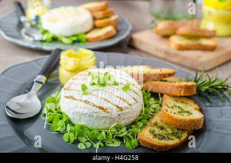 Grilled camembert with fresh herbs, herb crispy baguettes, Dijon mustard Stock Photo