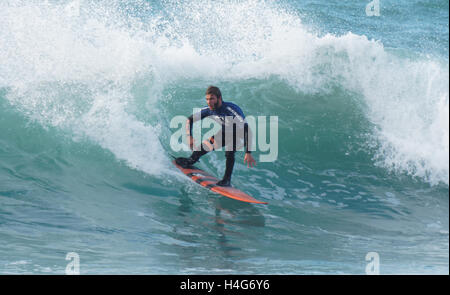 Student surfing contestants compete in large sunlit waves at Fistral beach Newquay, Cornwall. Stock Photo