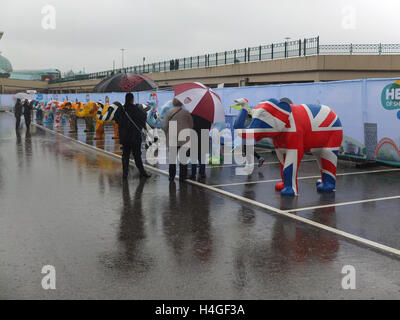 Meadowhall, Sheffield, UK. 16th October 2016. UK Weather: Despite heavy rain, a crowd of people attends the Herd of Sheffield Farewell event in the car park of Meadowhall shopping centre. The herd of 58 elephants, which have each been designed by a different artist, have been spread across various Sheffield locations over the summer. They have been brought together for the first time this weekend prior to being auctioned off to raise funds for Sheffield Children's Hospital Charity. Richard Bradley / Alamy Live News Stock Photo