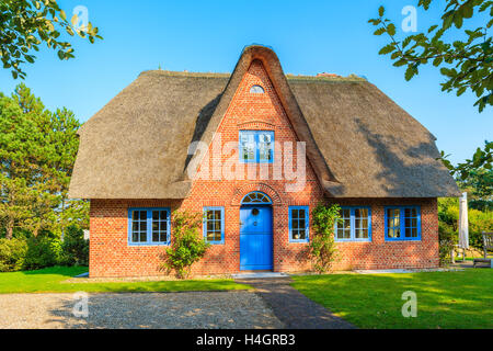 Traditional red brick house with thatched roof in Kampen village on Sylt island, Germany Stock Photo